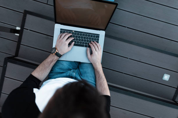 istock Young man freelancer working on a modern laptop. Top view of a young busy worker. Remote work. Work time. 2167446162