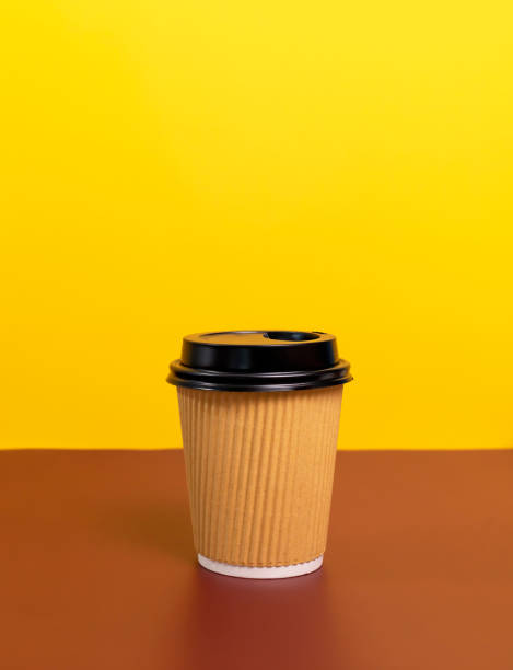 istock Mockup Brown Beige Paper Drinks Mug, Cup with Black Lid On Brown Yellow Background. Copy Space. On the Go Food Service Application. Vertical Plane, Eco Hot Beverage Tumbler 2167446503