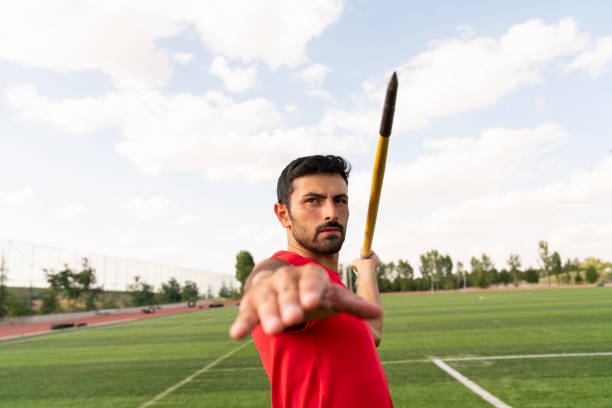 Young man in a motion throwing a javelin on a competition.