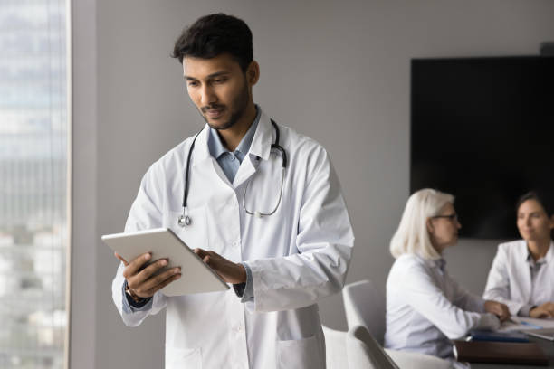 istock Focused Indian general practitioner wears white coat use digital tablet 2167454783