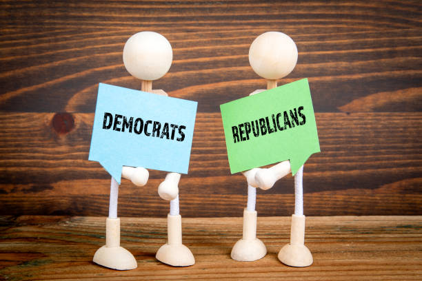 istock Democrats vs Republicans. Two speech bubbles and miniature people on a wooden texture background 2167456448