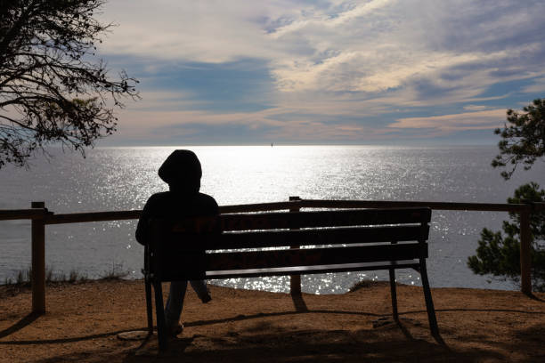 istock A person is sitting on a bench overlooking the ocean 2167458335