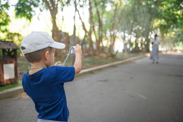 istock Young boy with camera capturing a moment in a verdant park setting 2167462003