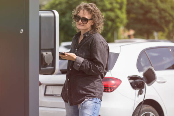 istock woman charges her car at a charging station 2167462399