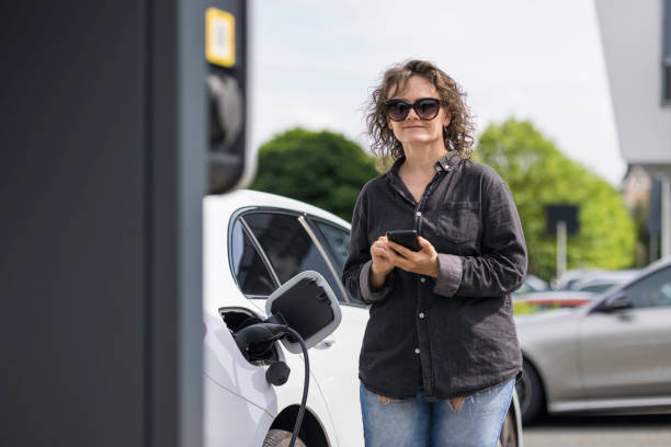 istock woman charges her car at a charging station 2167462419