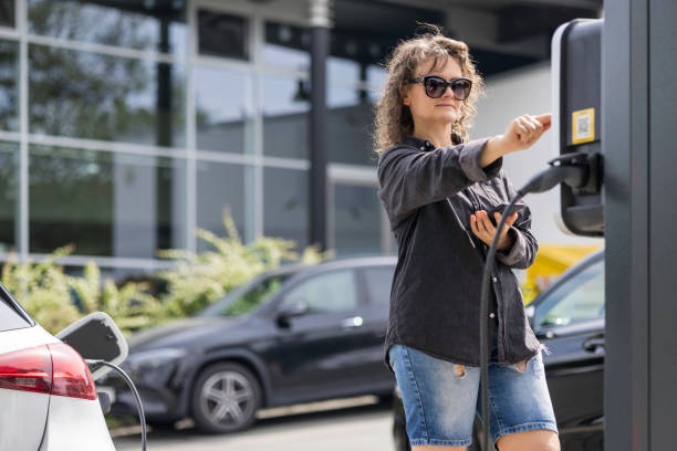 istock woman charges her car at a charging station 2167462427