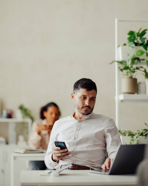 Professional Business Man Using Smartphone and Laptop in Office