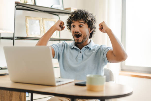 istock Excited young Indian man celebrating success while working from home office win money 2167466354
