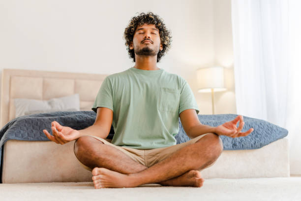 istock Indian man practicing meditation sitting in lotus pose at home 2167466417