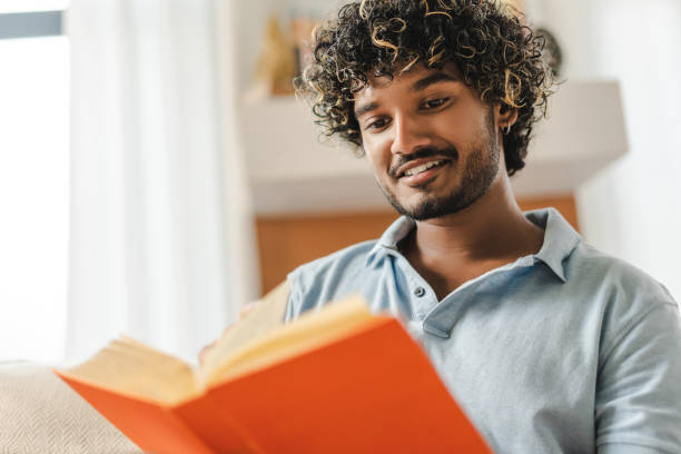 istock Handsome Indian man smiling and reading book at home, hobby concept 2167466852