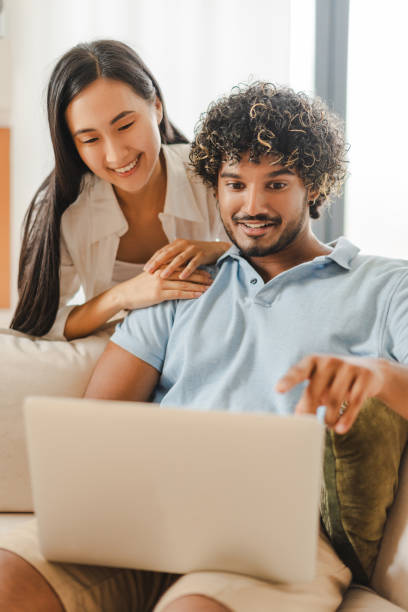 istock Happy couple browsing internet using laptop at home on sofa 2167466883