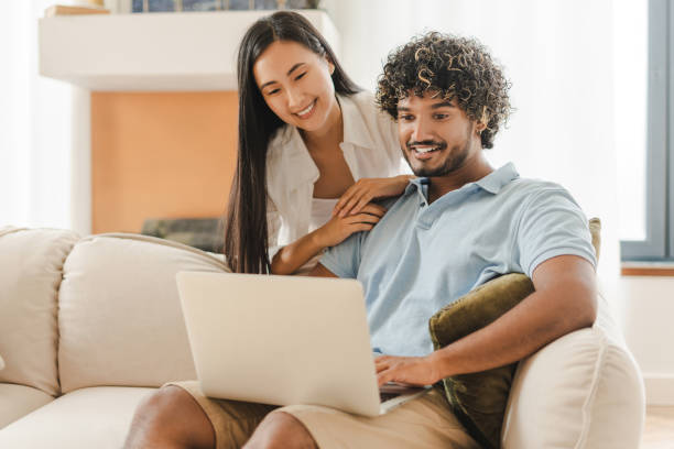 istock Happy couple relaxing on sofa using laptop at home ordering, online shopping 2167466886