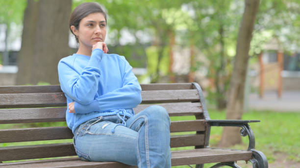 istock Pensive Indian Woman Thinking while Sitting Outdoor on Bench 2167468645