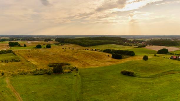 A breathtaking rural landscape featuring vast green fields and gentle hills under a glowing sunset. The peaceful countryside offers a serene view of nature's beauty, perfect for editorial use.