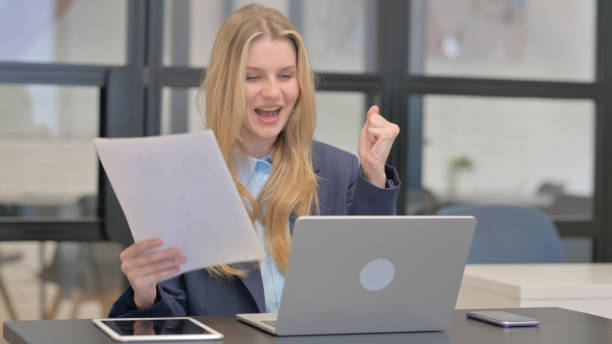 istock Excited Young Businesswoman Celebrating Success while Multi Tasking at Work 2167471908
