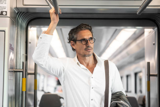 Mature businessman travelling by train standing inside and looking away