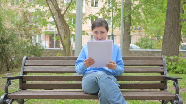 istock Indian Woman Celebrating while Reading Documents while Sitting Outdoor on Bench 2167475093