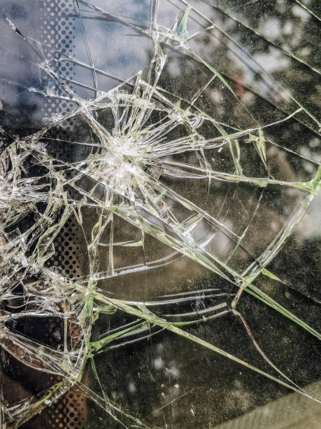 istock Shattered car window, displaying intricate patterns of cracked glass, vertical close-up 2167484894