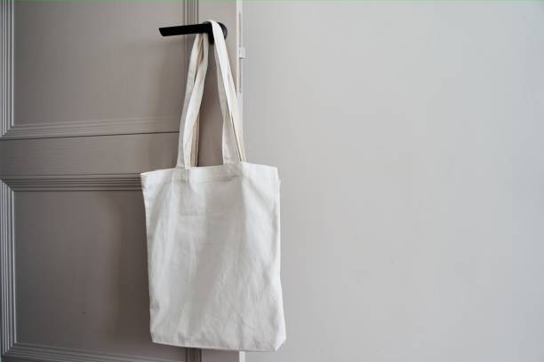 istock White eco friendly bag hanging on the door handle. Canvas tote bag 2167489154