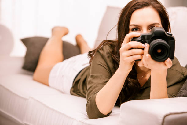 istock Woman relaxing on couch taking photos with camera 2167489888