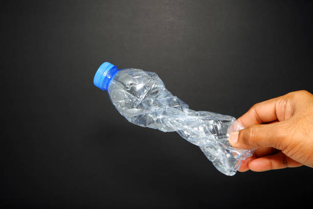 istock Holding a crushed plastic bottle with dark background close-up view 2167493843