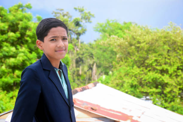a school boy standing and give pose in his uniform with green background