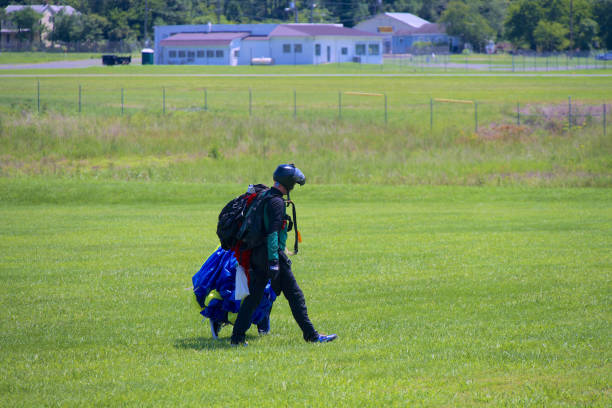 Orange, Virginia, USA - August 11, 2024: A “Sky Dive Orange” instructor walks off the landing zone alongside a student after completing a tandem dive.