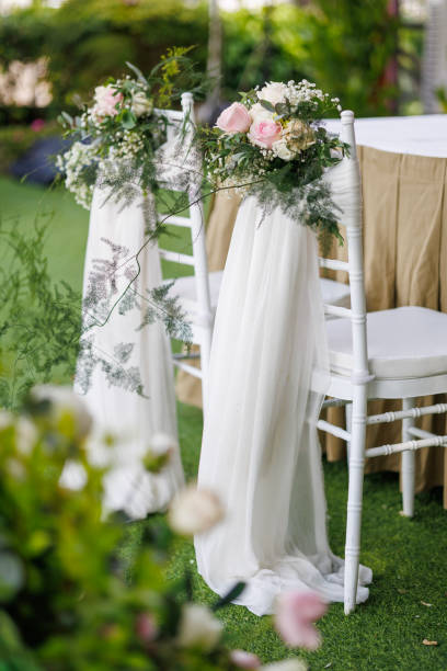 istock Chairs for a wedding reception are elegantly decorated with fabric and flowers, set up for an outdoor wedding ceremony. 2167498931