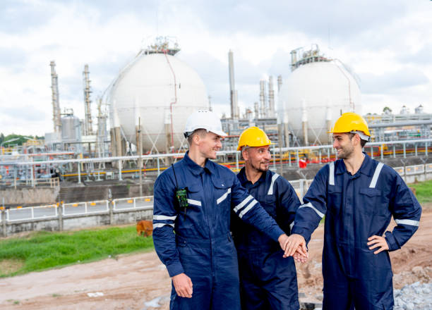 istock Factory engineer or technician workers stand and join hands together in front of tank of refining and petrochemical factory with day light. 2167501900