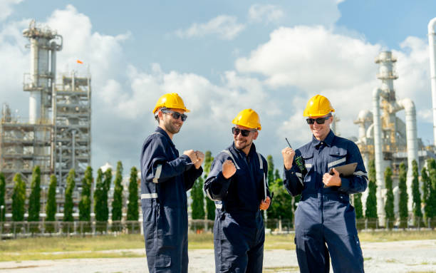 istock Group of factory engineer or technician workers stand with express happiness action in front of refining and petrochemical factory with day light. 2167502322