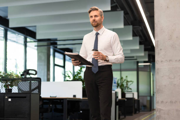 istock Businessman walking in office corridor with documents and takeaway coffee 2167507317