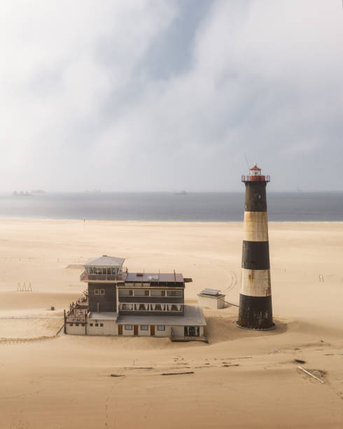 The oceanfront lighthouse at Sandwich Harbour in Namibia, Africa. Landscape drone photography