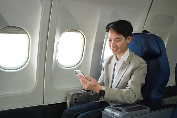 istock Handsome businessman in suit using smart phone while sitting on comfortable seat in airplane cabin 2167511400