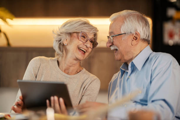 istock Cheerful senior couple laughing at dining table and holding tablet. 2167515585