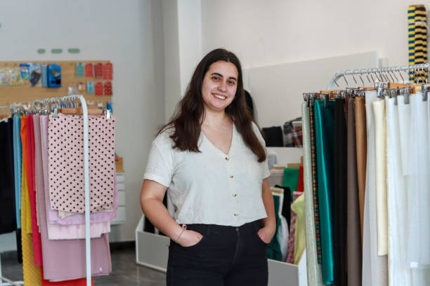 istock Young female retail store owner standing confidently among fabric rolls in a modern textile shop 2167518559