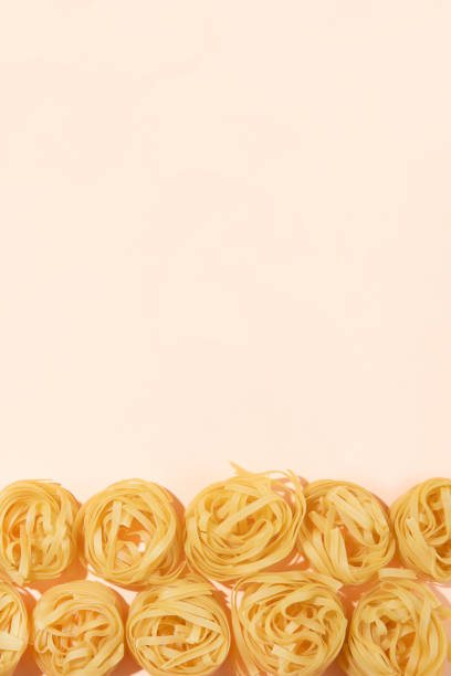 Italian pasta tagliatelle in a row on pink background