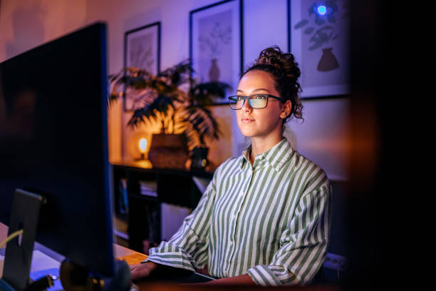 istock Young beautiful businesswoman with eyeglasses using desktop PC while working at home office during night time 2167520770