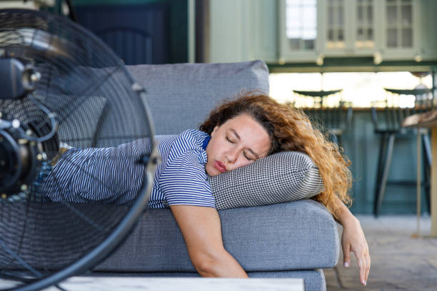 mladá žena ležící doma před elektrickým ventilátorem, přemožená horkem - vějíř - stock snímky, obrázky a fotky