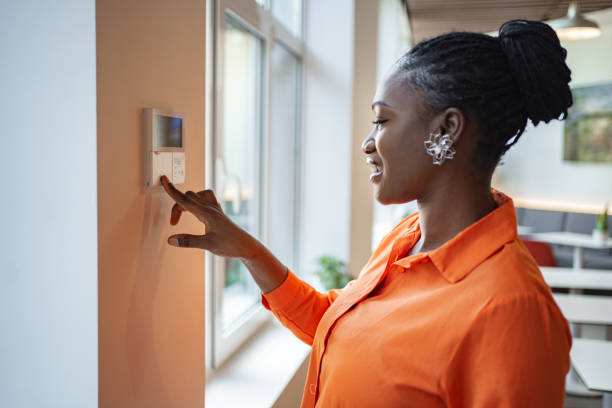 istock Black woman adjusting central heating temperature on thermostat 2167521358