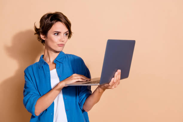 istock Photo of young woman programmer in it industry working using netbook trying fix junior specialist bug isolated on beige color background 2167523763