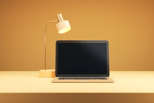 Laptop and lamp on desk in modern orange-themed workspace. 3D Rendering