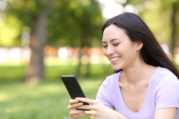 istock Happy asian woman checking cell phone in a park 2167529444