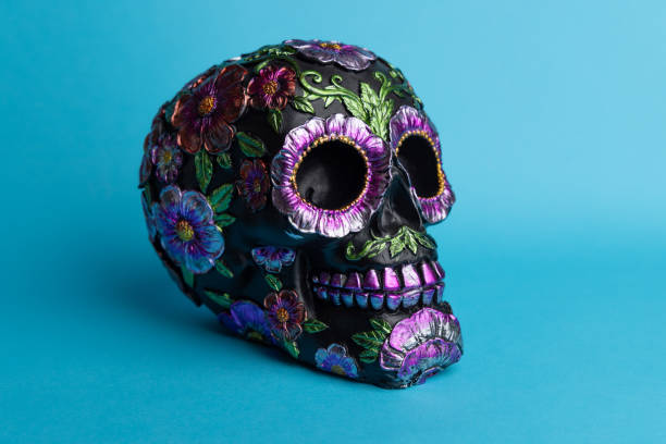 istock A detailed black skull decorated with shiny metallic flowers, set on a blue backdrop 2167531050