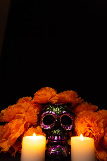 istock Vertical image featuring a black skull with metallic floral embellishments, framed by a marigold garland and flanked by lit candles 2167531345