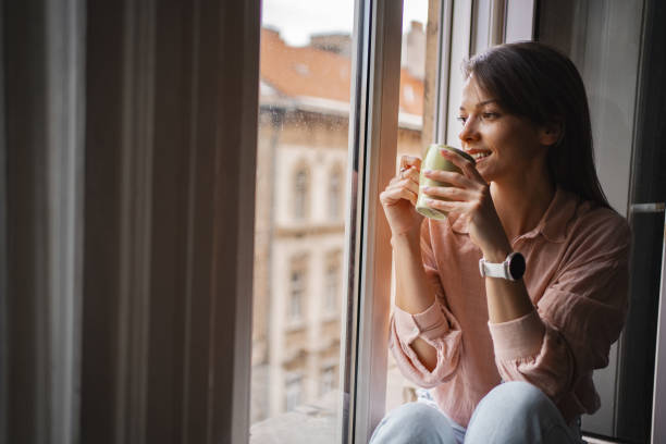 istock Woman enjoying a warm beverage while sitting by a window in Budapest 2167532013