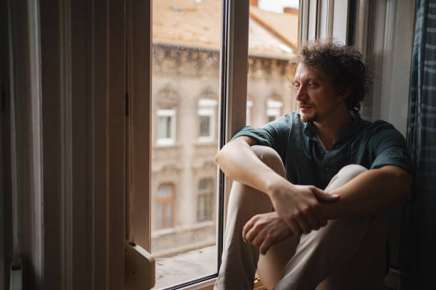 istock A man reflects while sitting by the window in a Budapest apartment, contemplating life during a quiet afternoon 2167532532