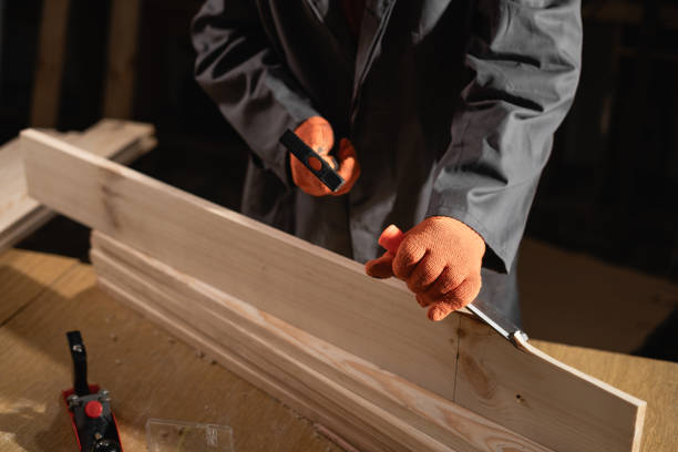 profession, carpentry and woodwork concept. Male carpenter with hammer and chisel processing wood plank, close-up