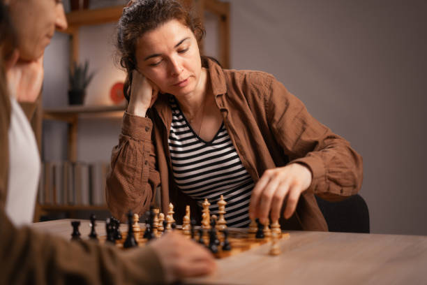 istock Two women playing chess at home, focused on the game, enjoying leisure time 2167536701