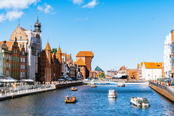 View of Motława River with Medieval Crane and Historic Buildings on a Sunny Day in Gdańsk. stock photo