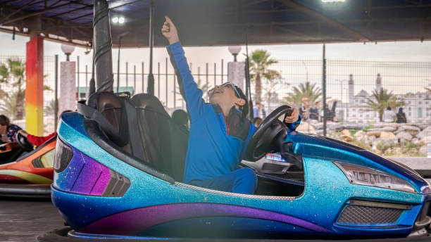 Bright blue and veil colors. Driving, holding the steering wheel and his arm raised, laughing and looking up.